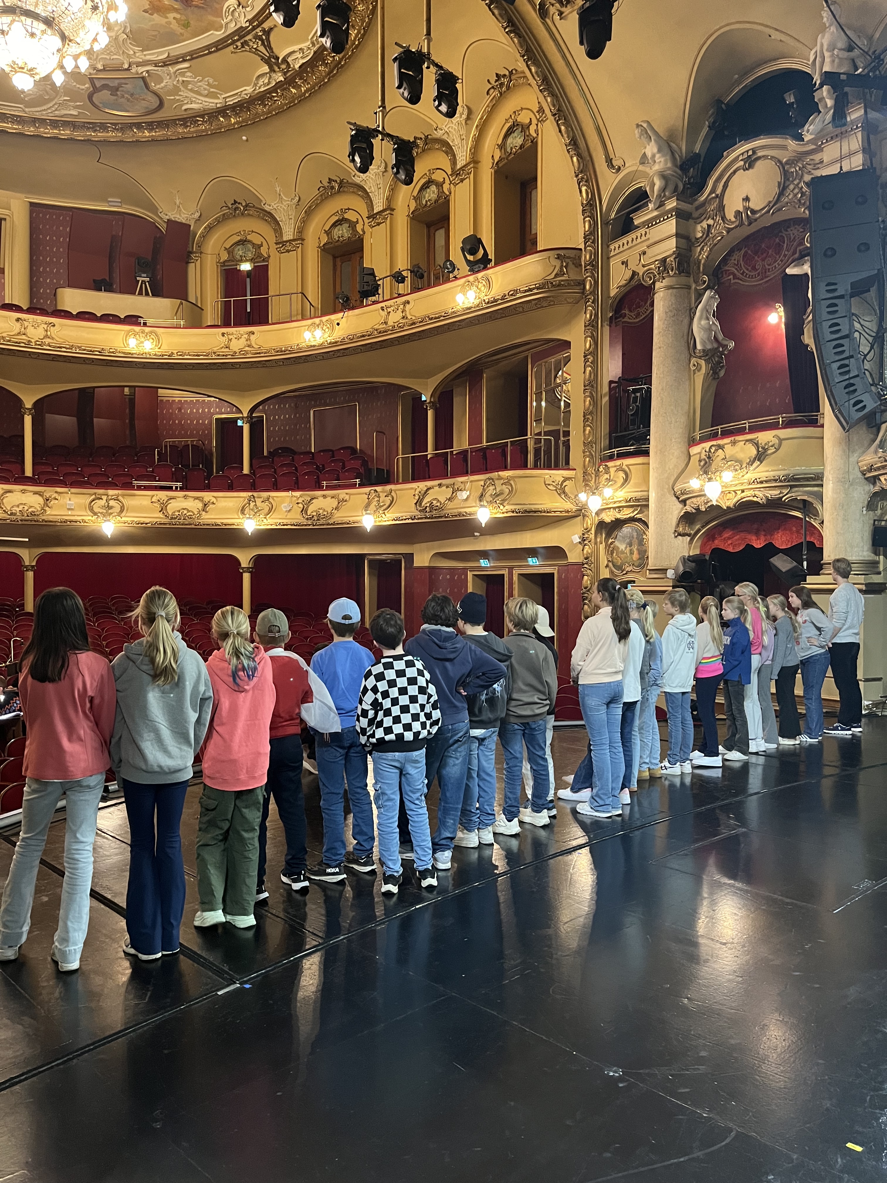 En gruppe mennesker i et stort rom med mange buer og gullvegger