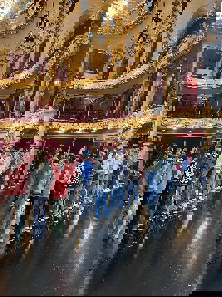 En gruppe mennesker i et stort rom med mange buer og gullvegger