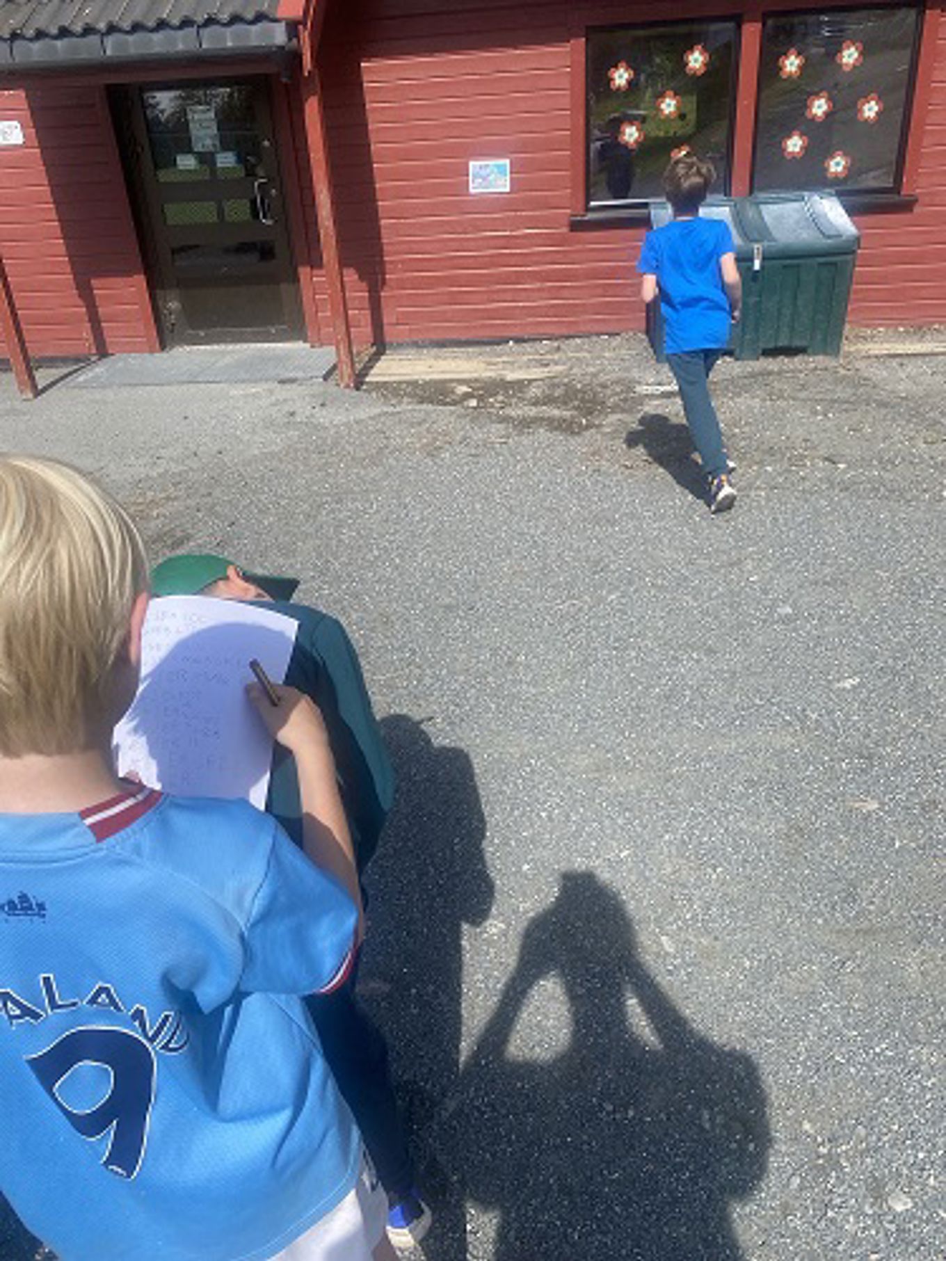 En gruppe mennesker som sitter på bakken utenfor en bygning