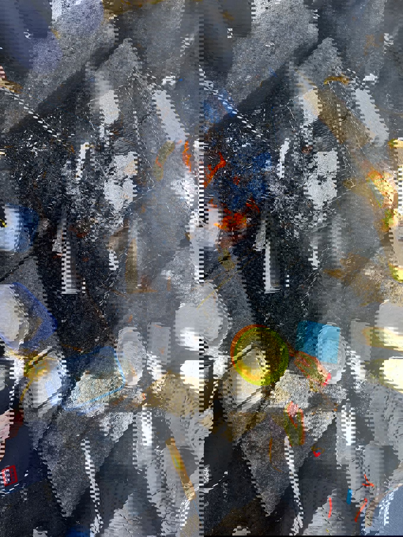 Foto: Marit Birgitte Heffermehl En person som sitter på bakken med en bøtte væske og et bål