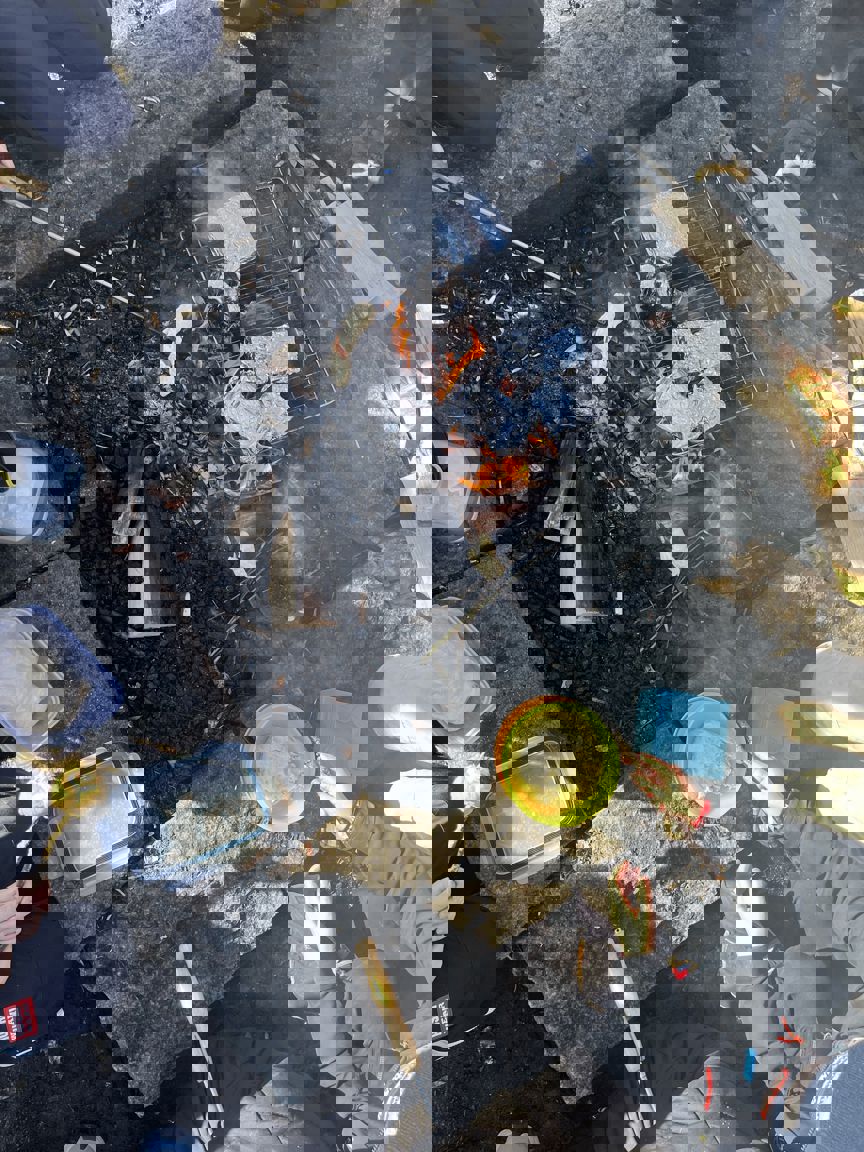 Foto: Marit Birgitte Heffermehl En person som sitter på bakken med en bøtte væske og et bål